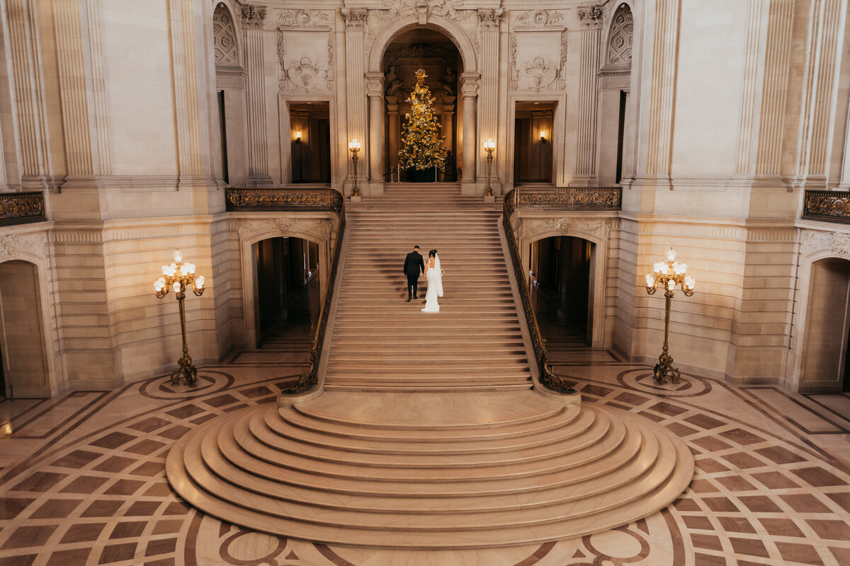 Loving this shot of the groom walking his bride up the beautiful stairs of San Francisco City Hall. This place is just gorgeous with all of the beautiful sculptures and perfect for a Christmas wedding.