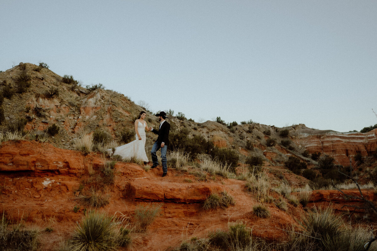 groom leading bride down the red dirt mesa at their texas elopement