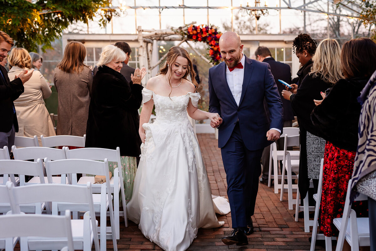 bride and groom exiting wedding ceremony in greenhouse at the Parm on the Pemi wedding Venue in Plymouth NH