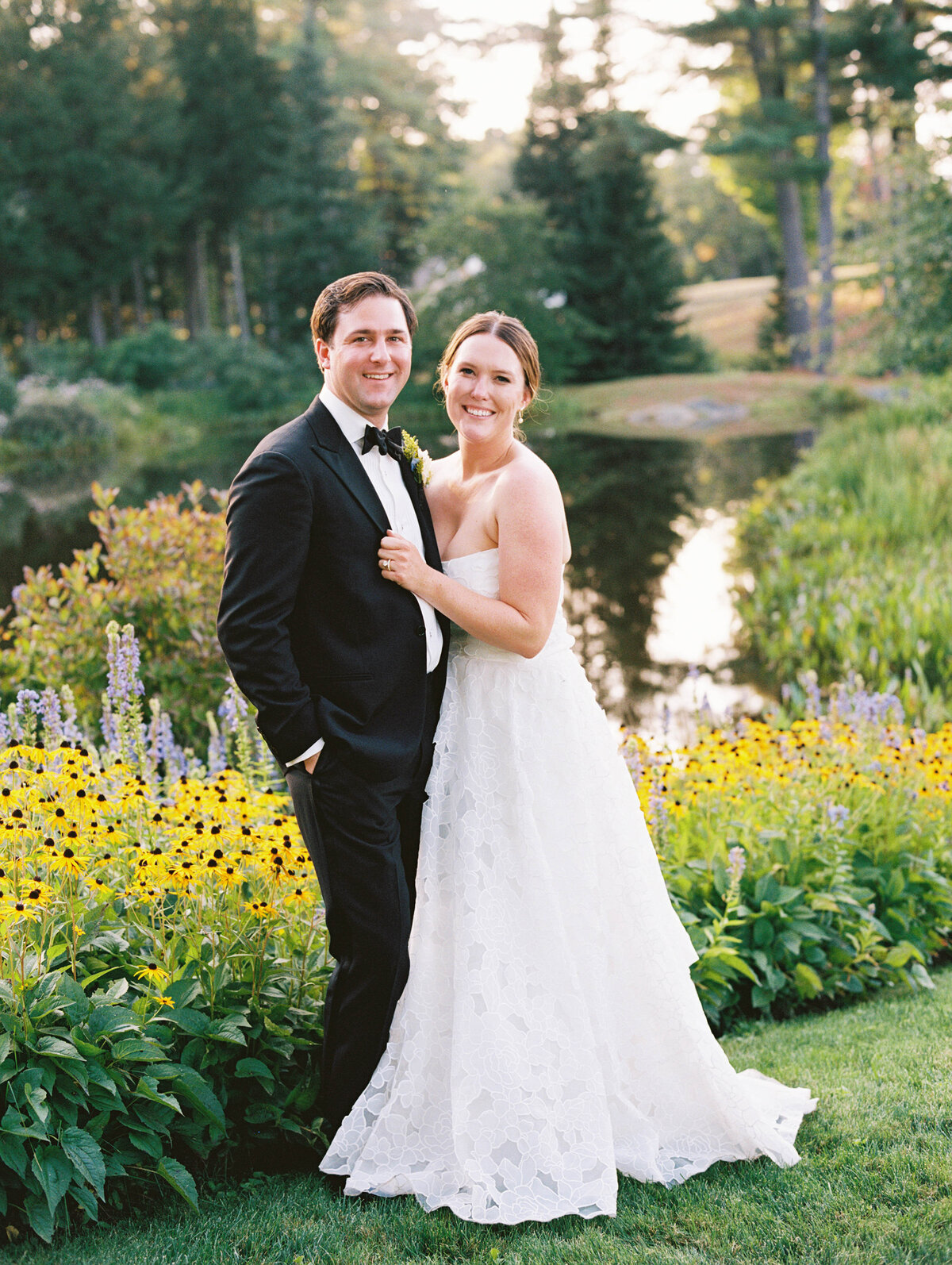 portrait of bride and groom with flowers and pond