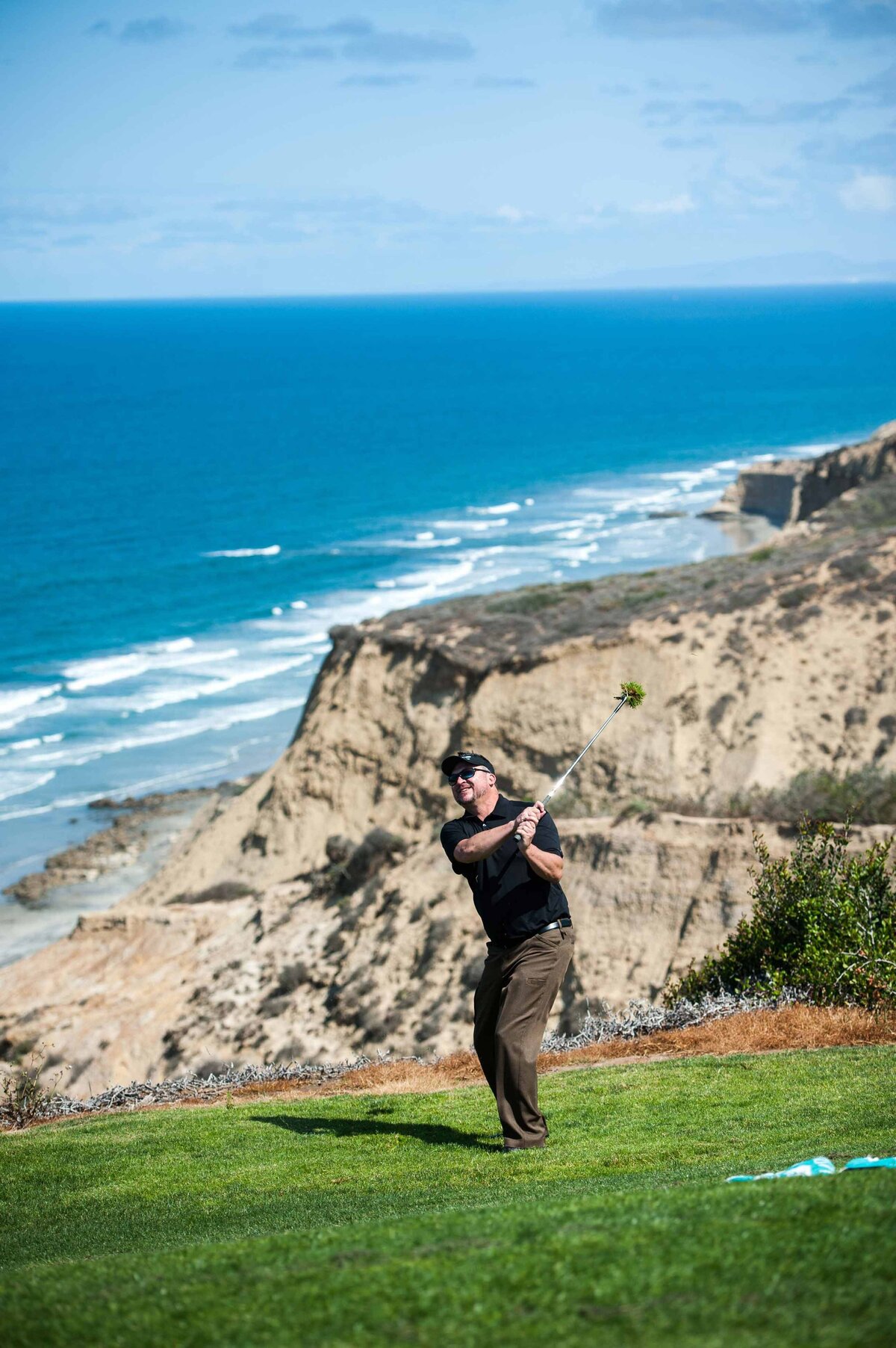 A man swings his club at Torrey Pines Golf Course in San Diego CA