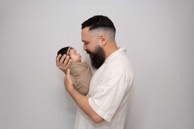 Father holding newborn close during Houston lifestyle family photography.