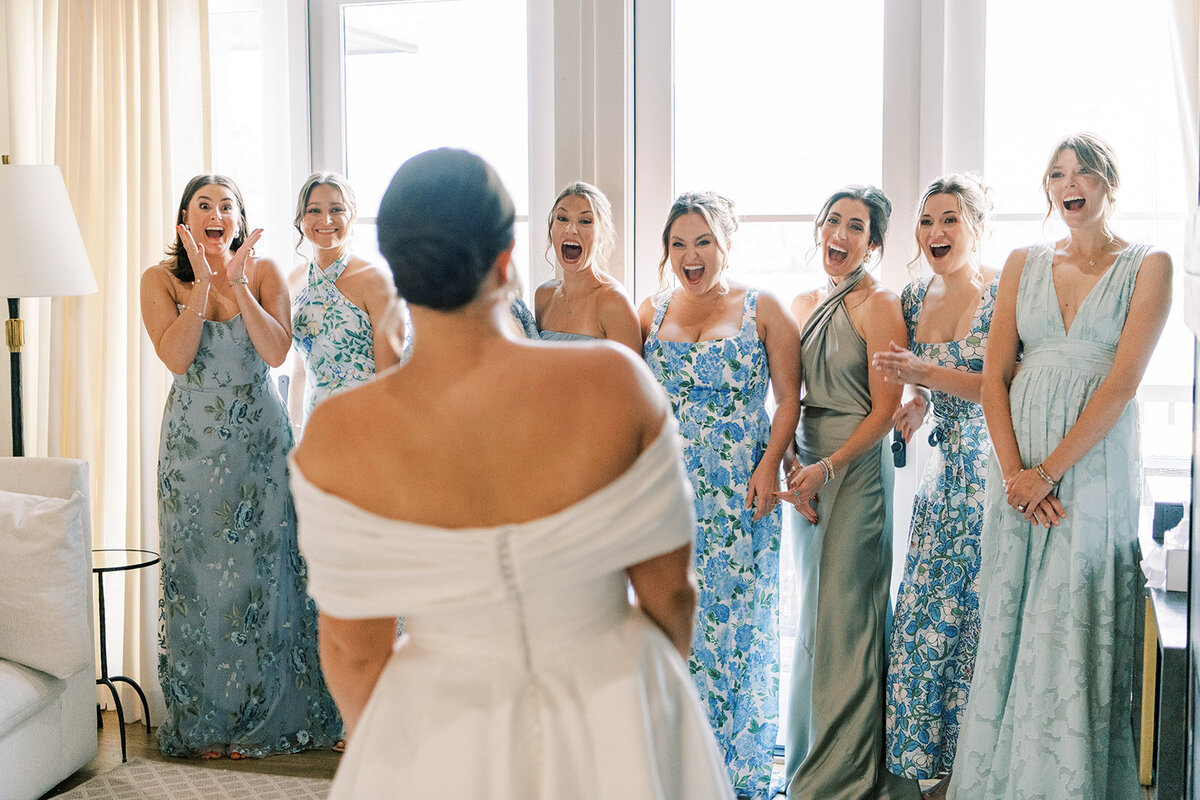 Bridesmaids react with excitement during the bride’s first look reveal before the ceremony.