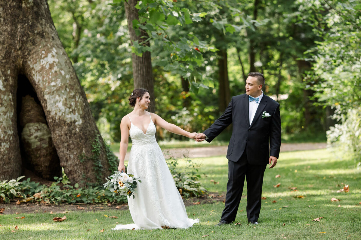 Bride and groom holding hands in front of sycamore tree