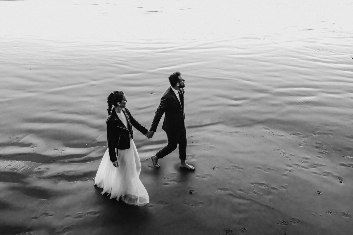 A bride and groom walk on the beach during their Oregon coast elopement.
