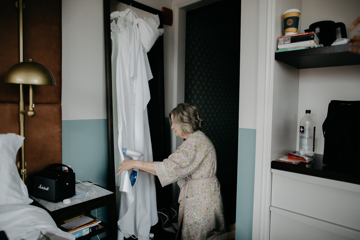 Mother of bride steaming brides stress hanging up in Chicago hotel room