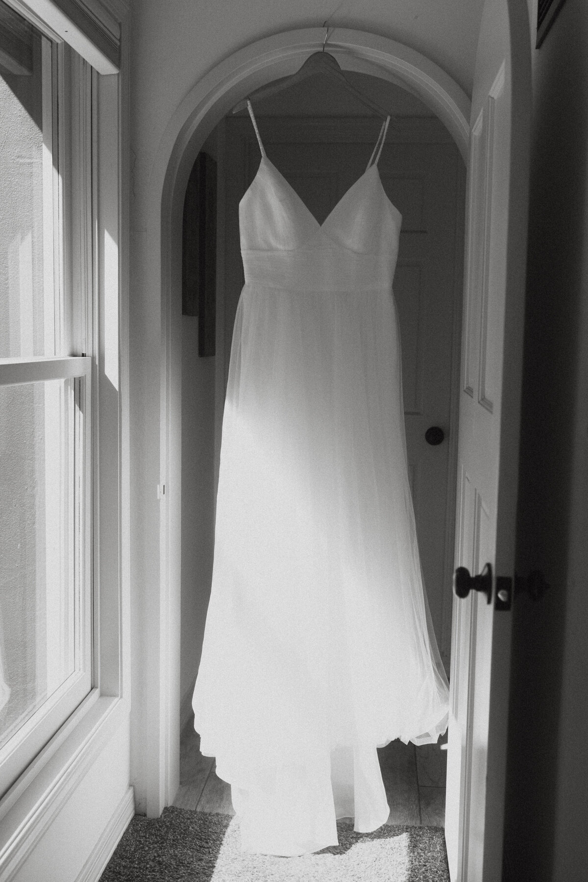 A wedding dress hanging in a door frame 