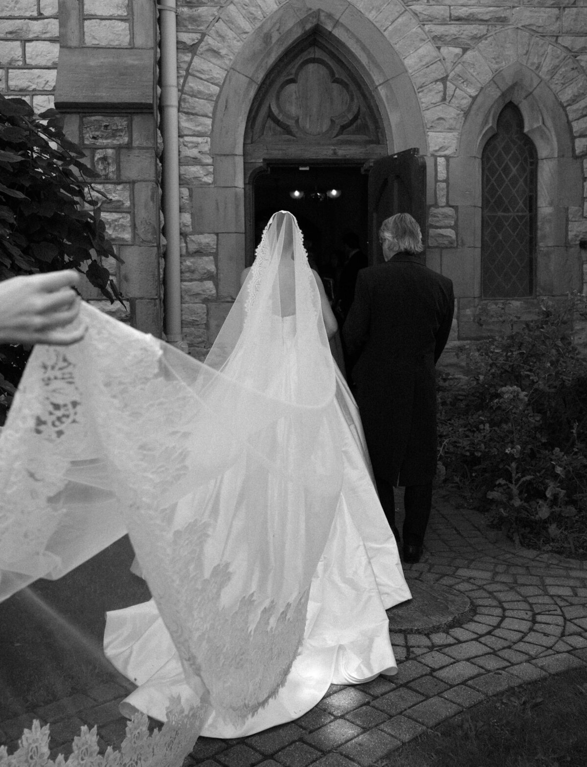 a bride's long lace veil is carried into Christ Church Detroit for her wedding ceremony