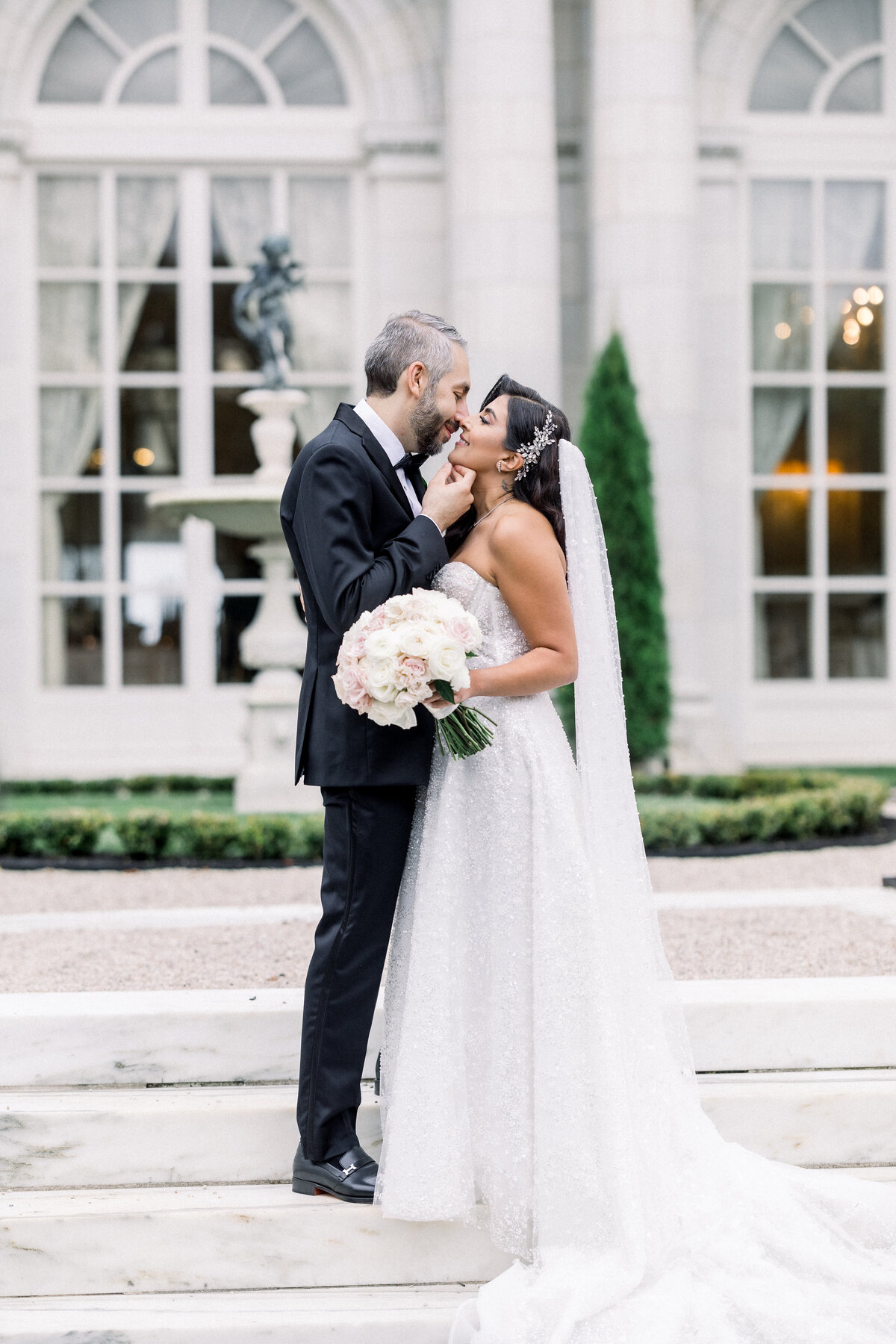 sophisticated bride and groom  kiss outside during wedding day portraits outside of rosecliff mansion in newport rhode island