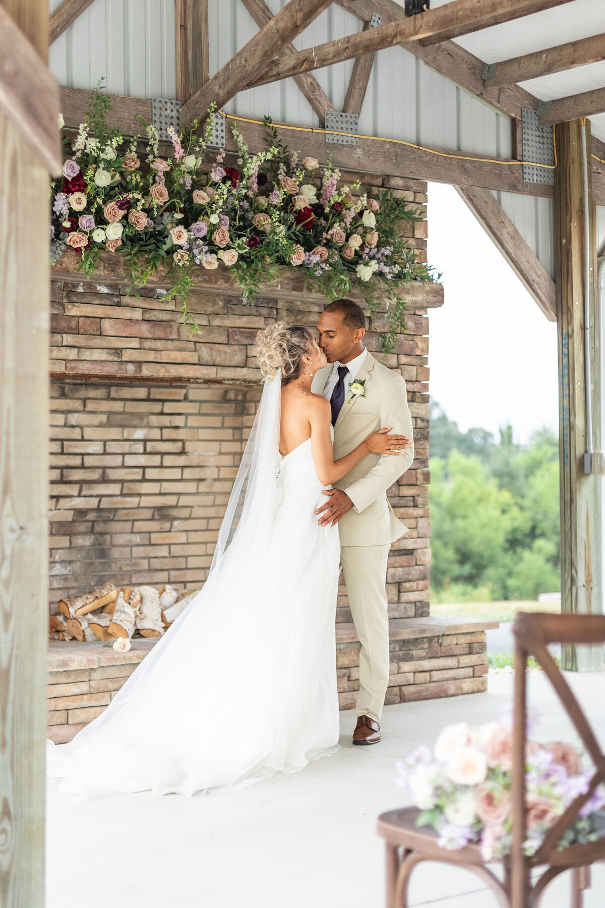 Bride and groom sharing a romantic moment in the rustic pavilion at Willow and Stone Events, surrounded by floral arrangements and countryside views.