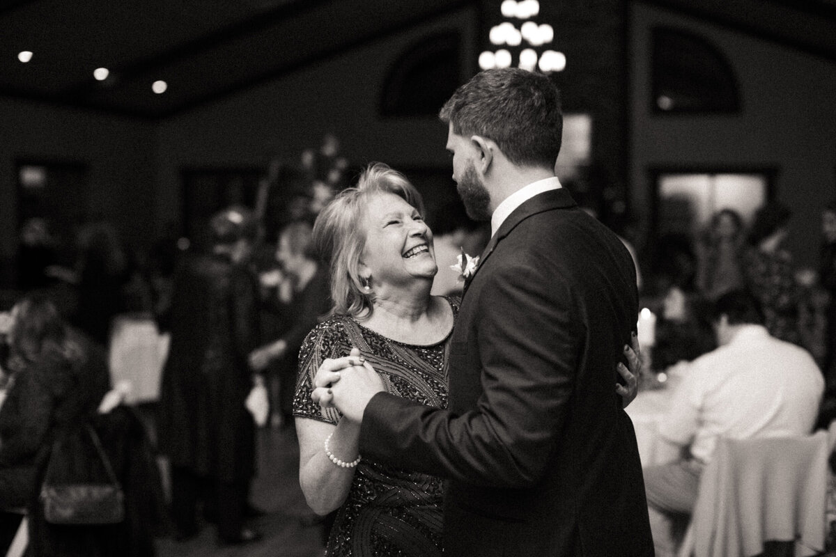 Groom's mom smiling up at her son during their mother-son dance