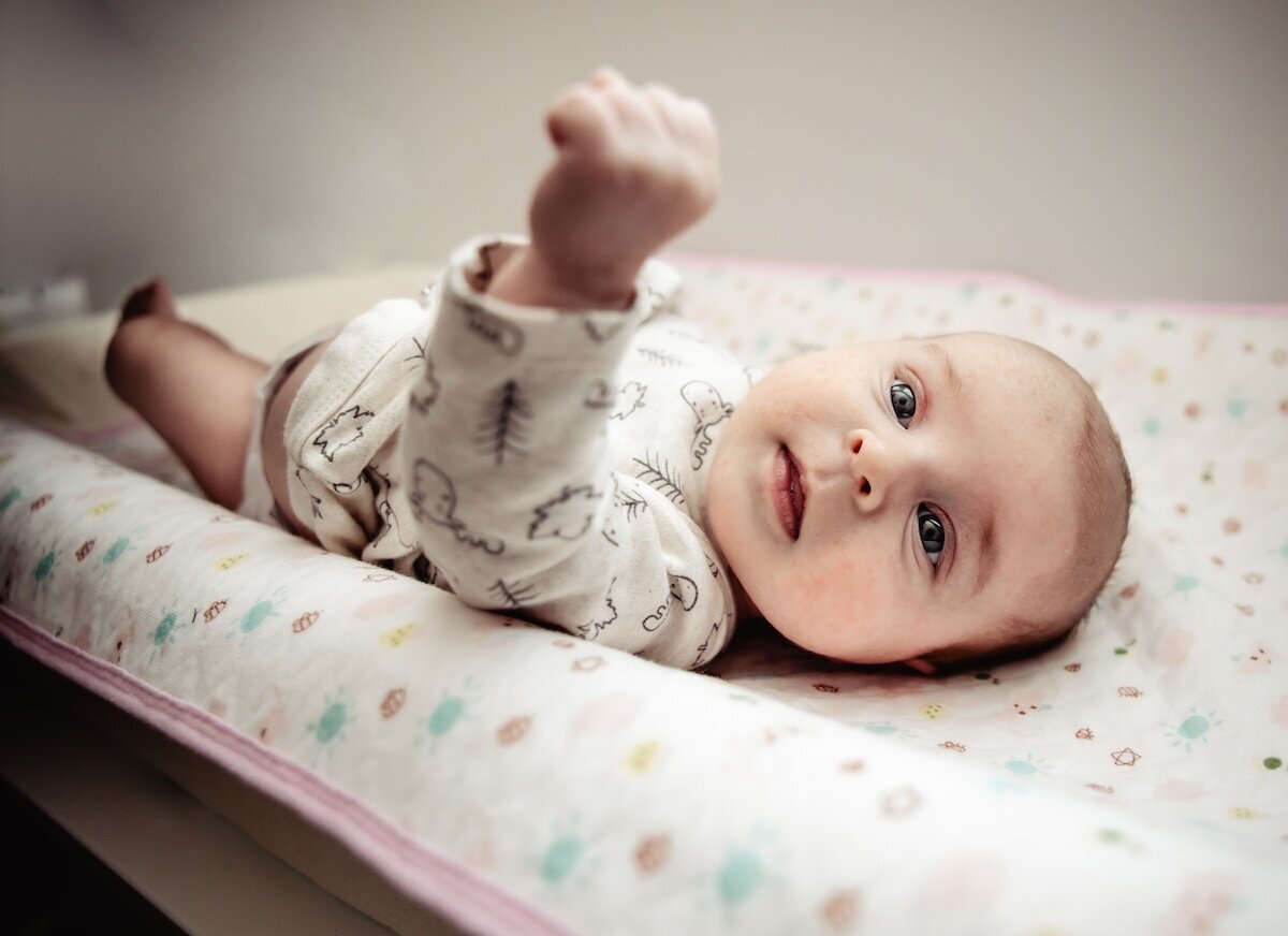 a newborn baby girl stretching out on her changing table