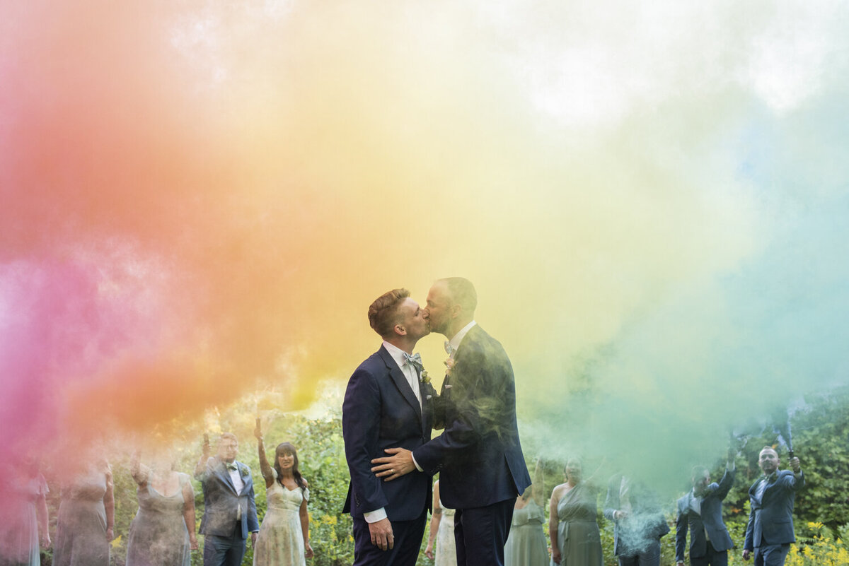 LGBTQ couple kissing during rainbow smoke bomb at Twisty Maple wedding