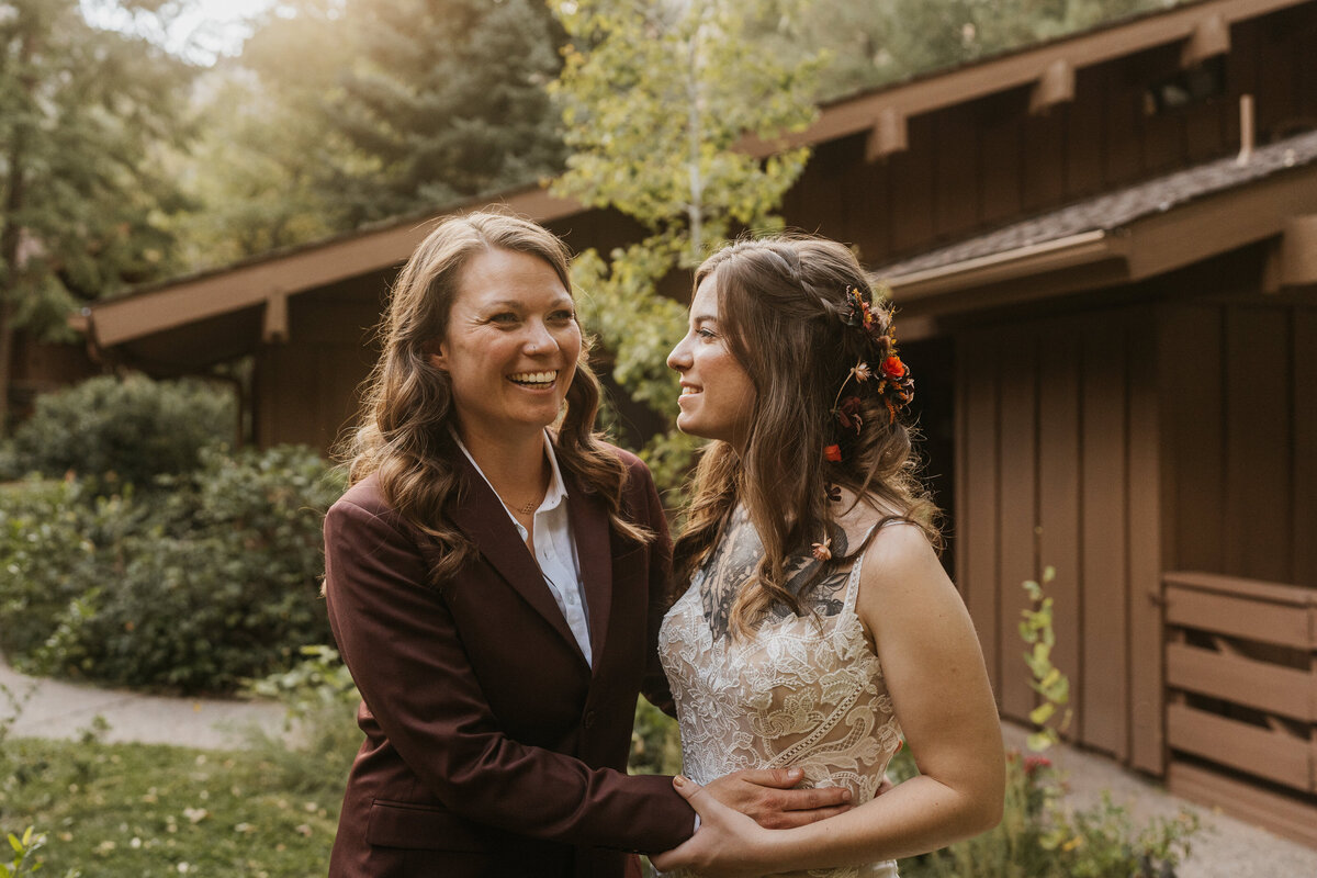 A newlywed couple with their arms around each other laughing 