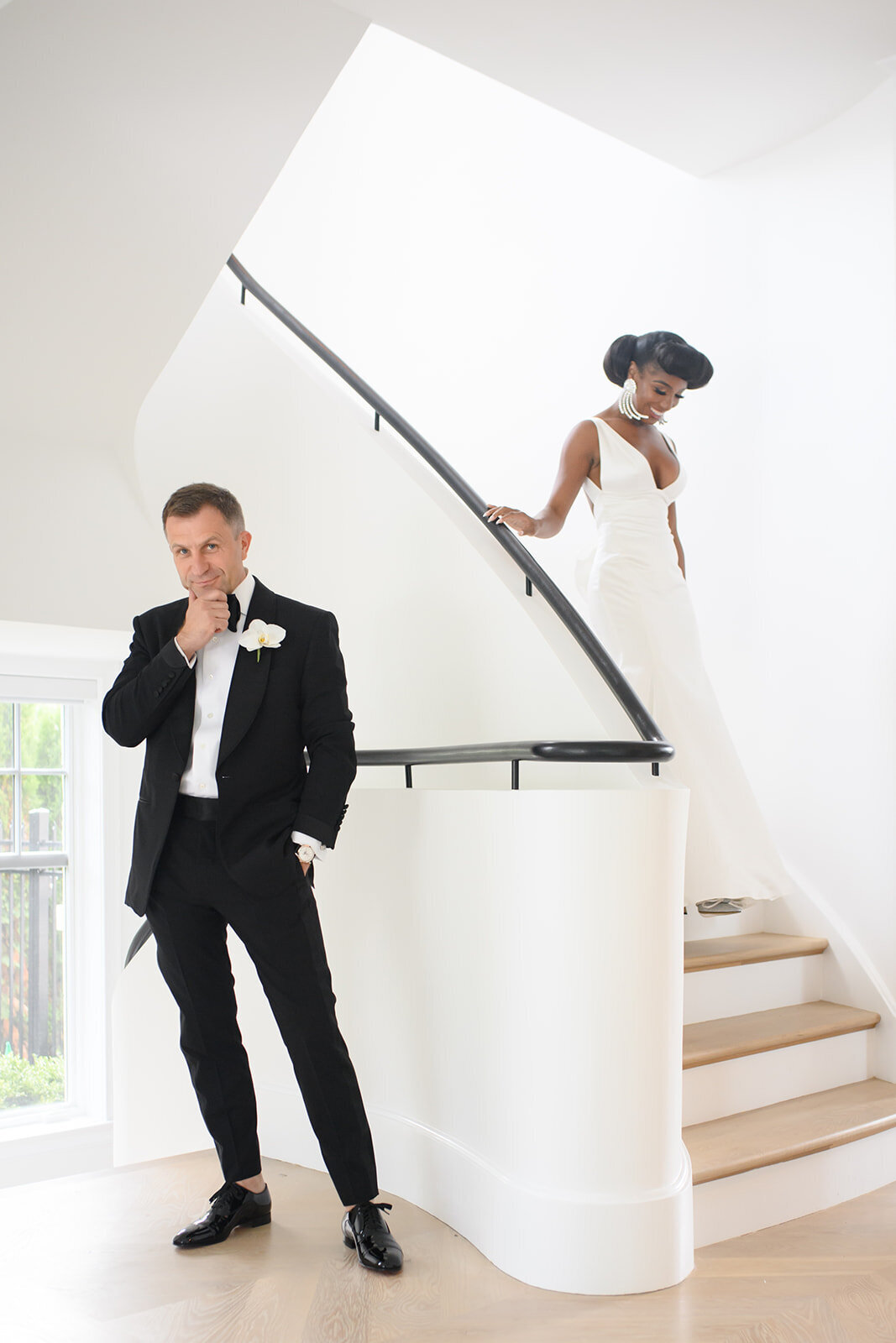 Bride and groom on a staircase, sharing a candid moment.