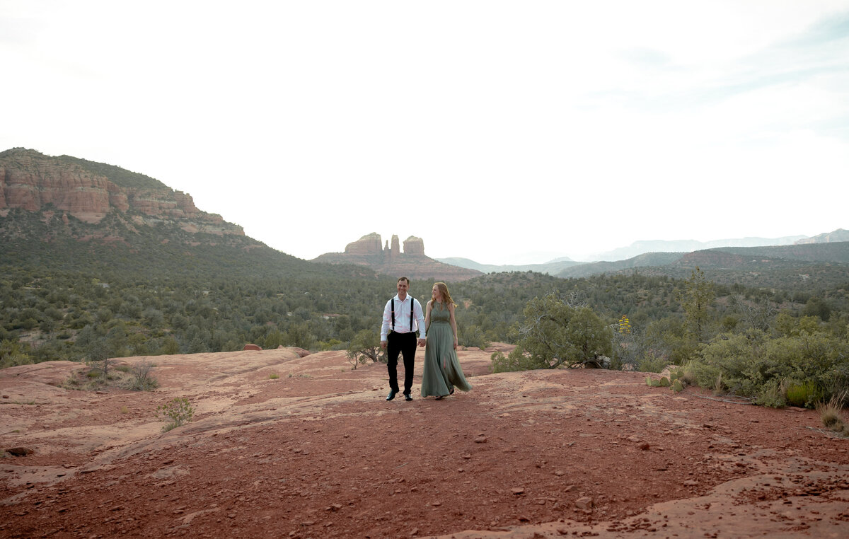 Couple standing against red rock backdrop during Sedona engagement session