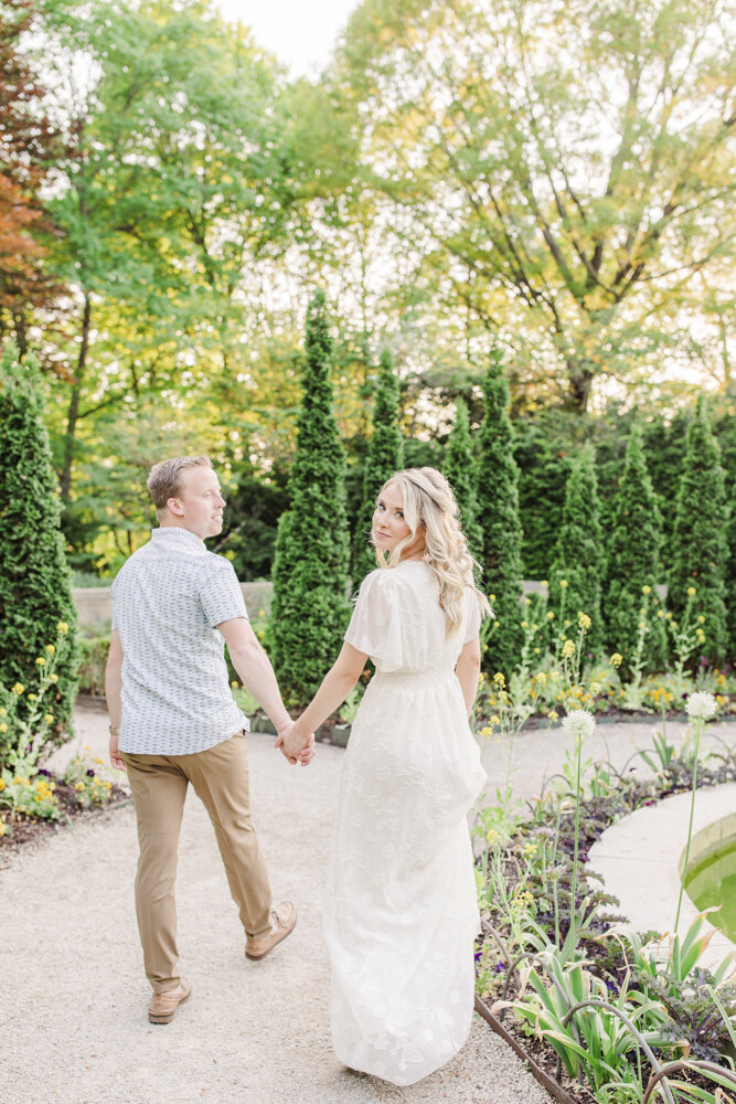 a man and woman walking in a garden while holding hands