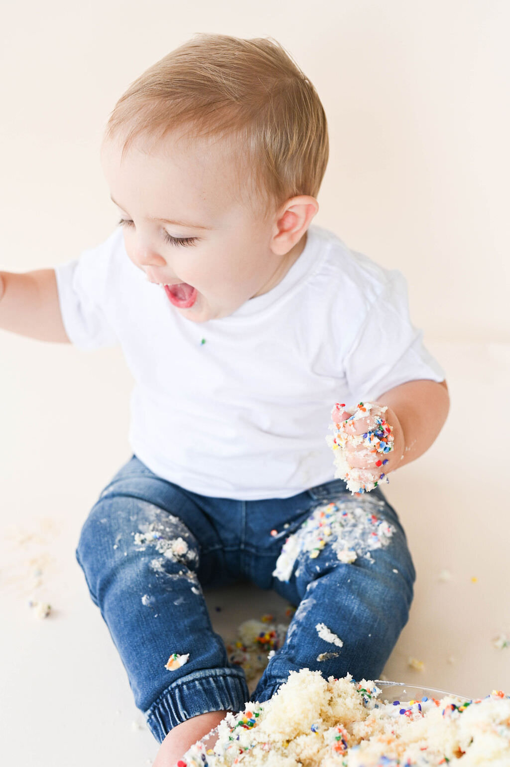 A baby playing with cake.