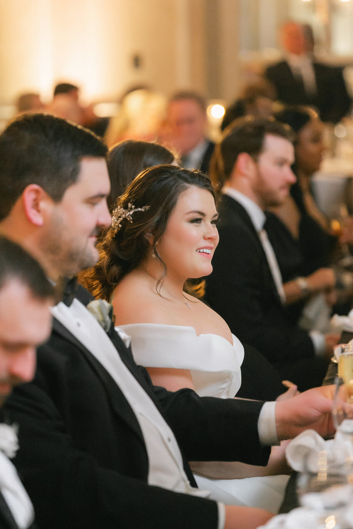 close-up of the bride smiling during wedding toasts at The Adolphus in Dallas, capturing a joyful and candid moment during the celebration.