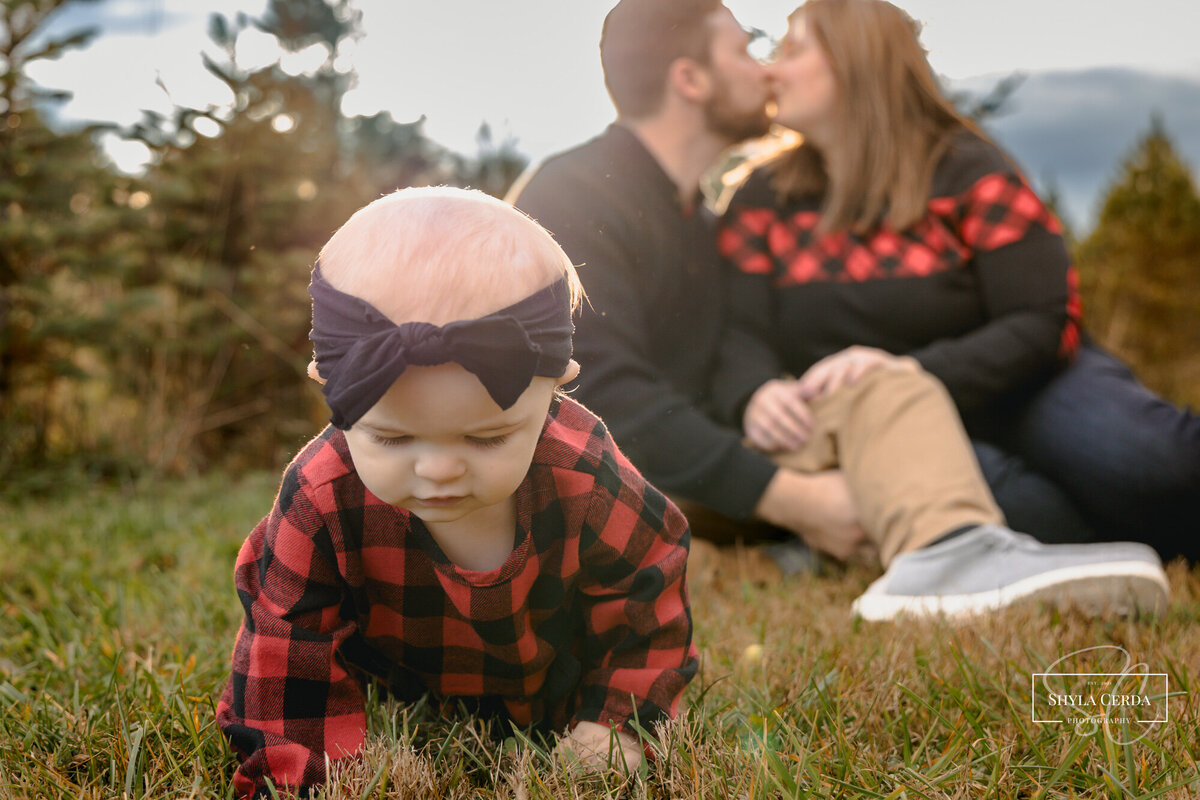 Baby playing in grass next to mom and dad
