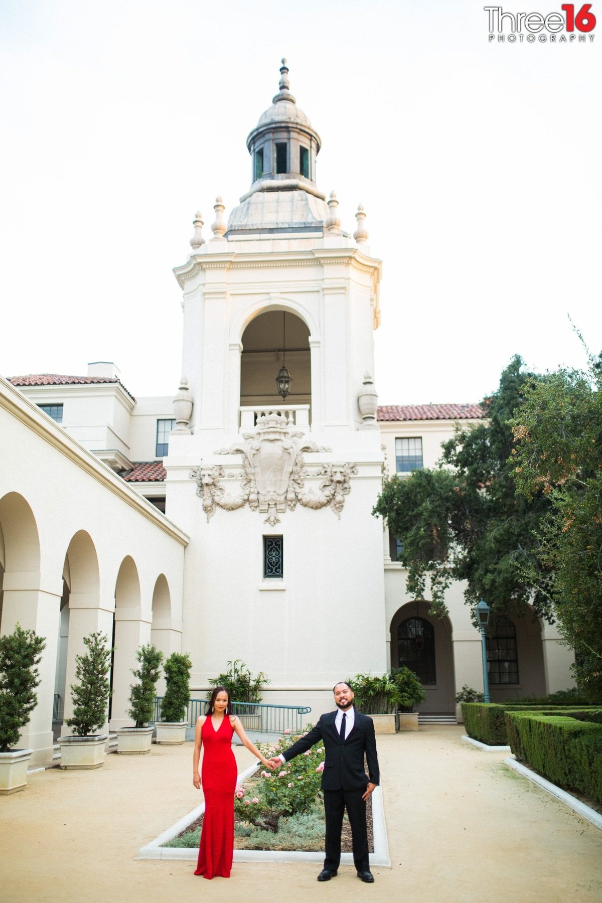 Engaged couple hold hands as they pose for photo shoot in the Pasadena City Hall garden courtyard