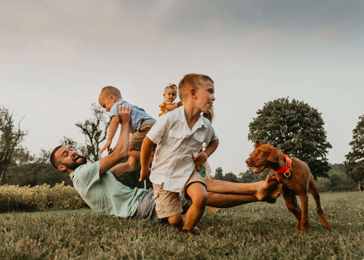 A Pittsburgh family playing with their dog in a field.