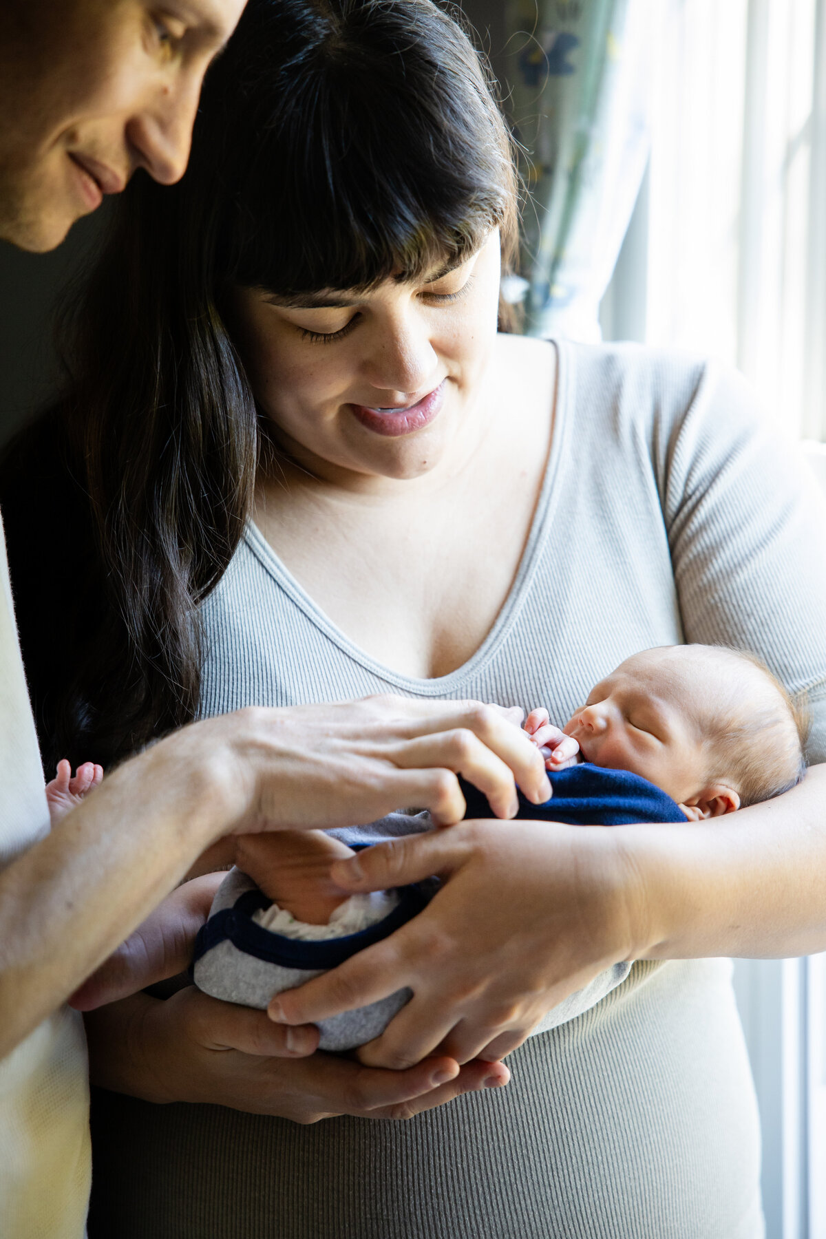 Baby in mom's arms by window in nursery