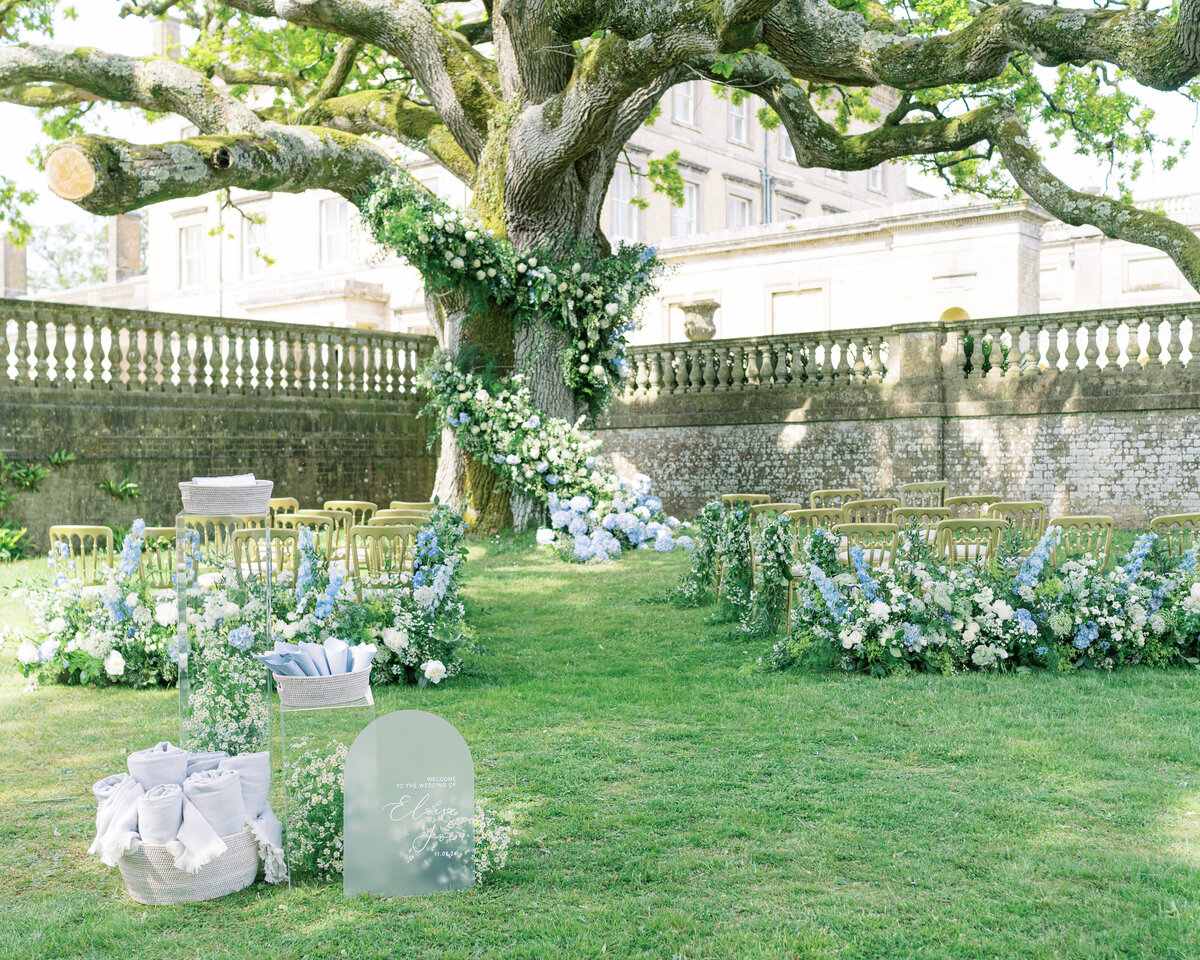 Outdoor ceremony with tree adorned with white and blue flowers