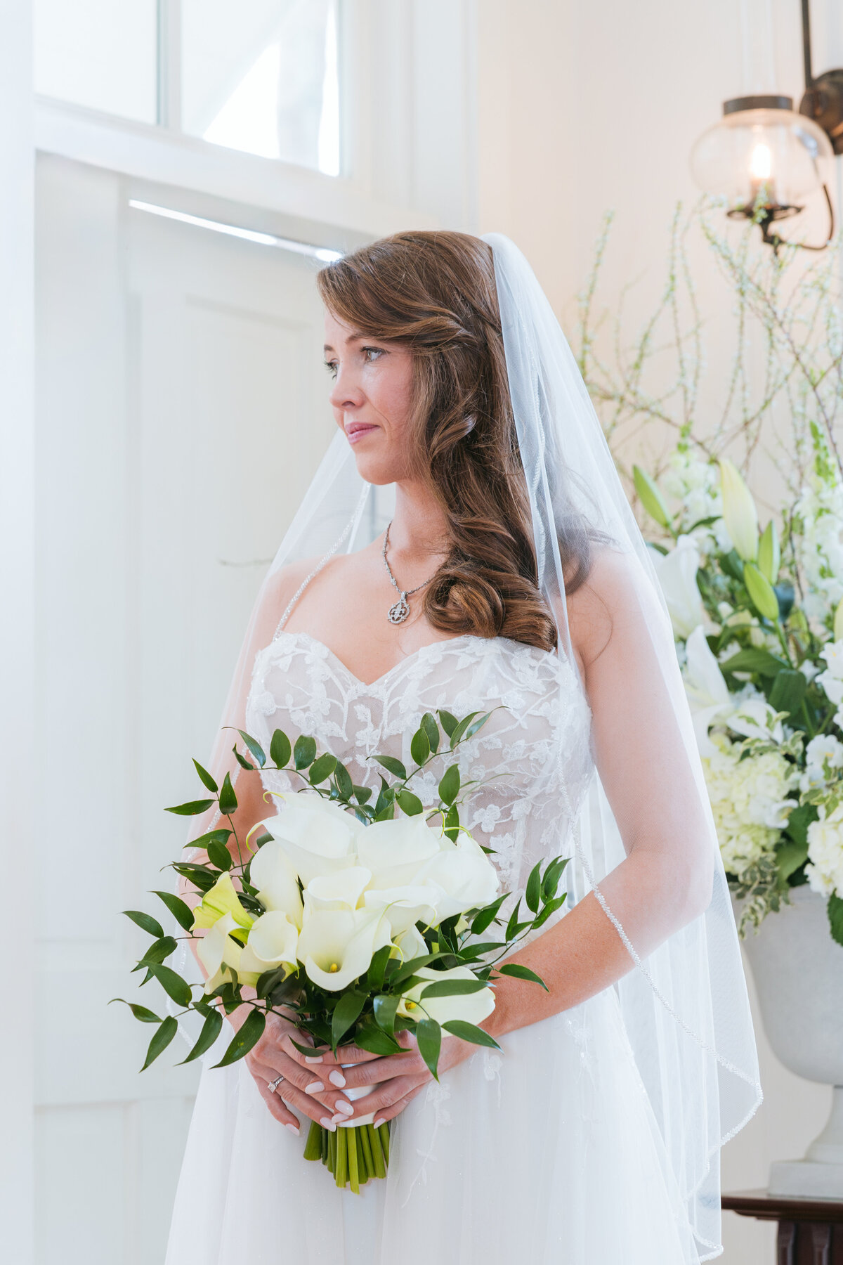 A stunning bride holds a bouquet of white calla lilies at her Palmetto Bluff wedding in Bluffton, SC. Captured in soft, natural light by Amia Marcell wedding Photographer.