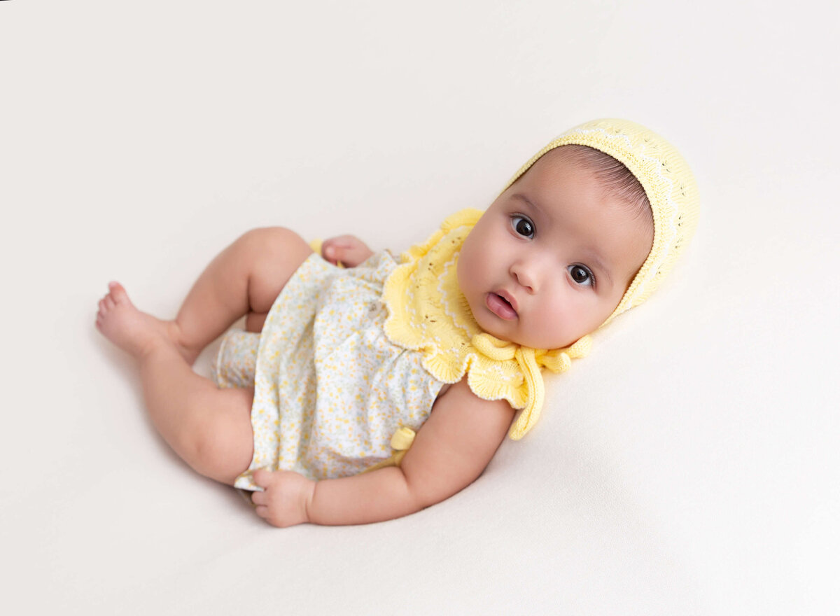 Baby girl lying on her back during a 3-month baby photoshoot captured in Brooklyn by Rochel Konik Photography