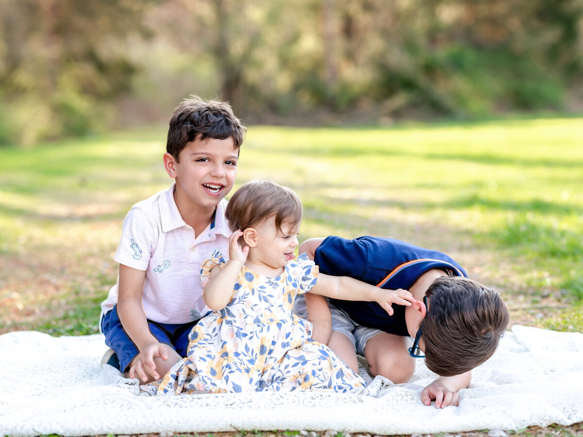 two brothers and sister sitting on lace blanket for family photos