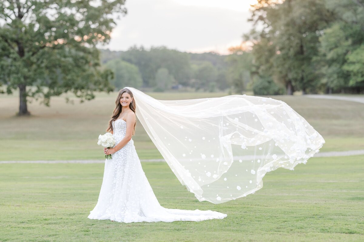 A bride smiles as her veil blows in the wind behind her