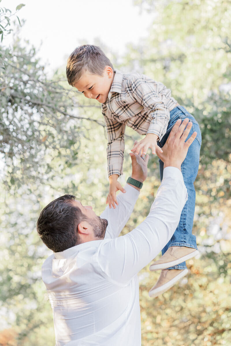 a father throws his young son in the air during their fall family pictures in Austin. 