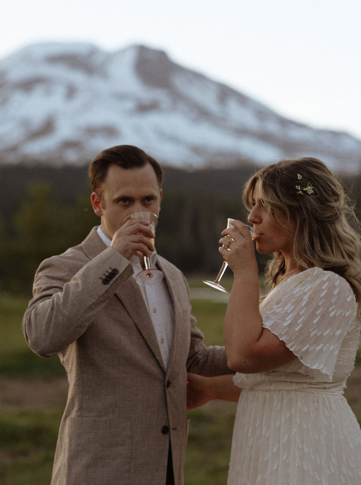 elopement couple sip champagne as they celebrate their elopement and stand in front of Mt. Bachelor