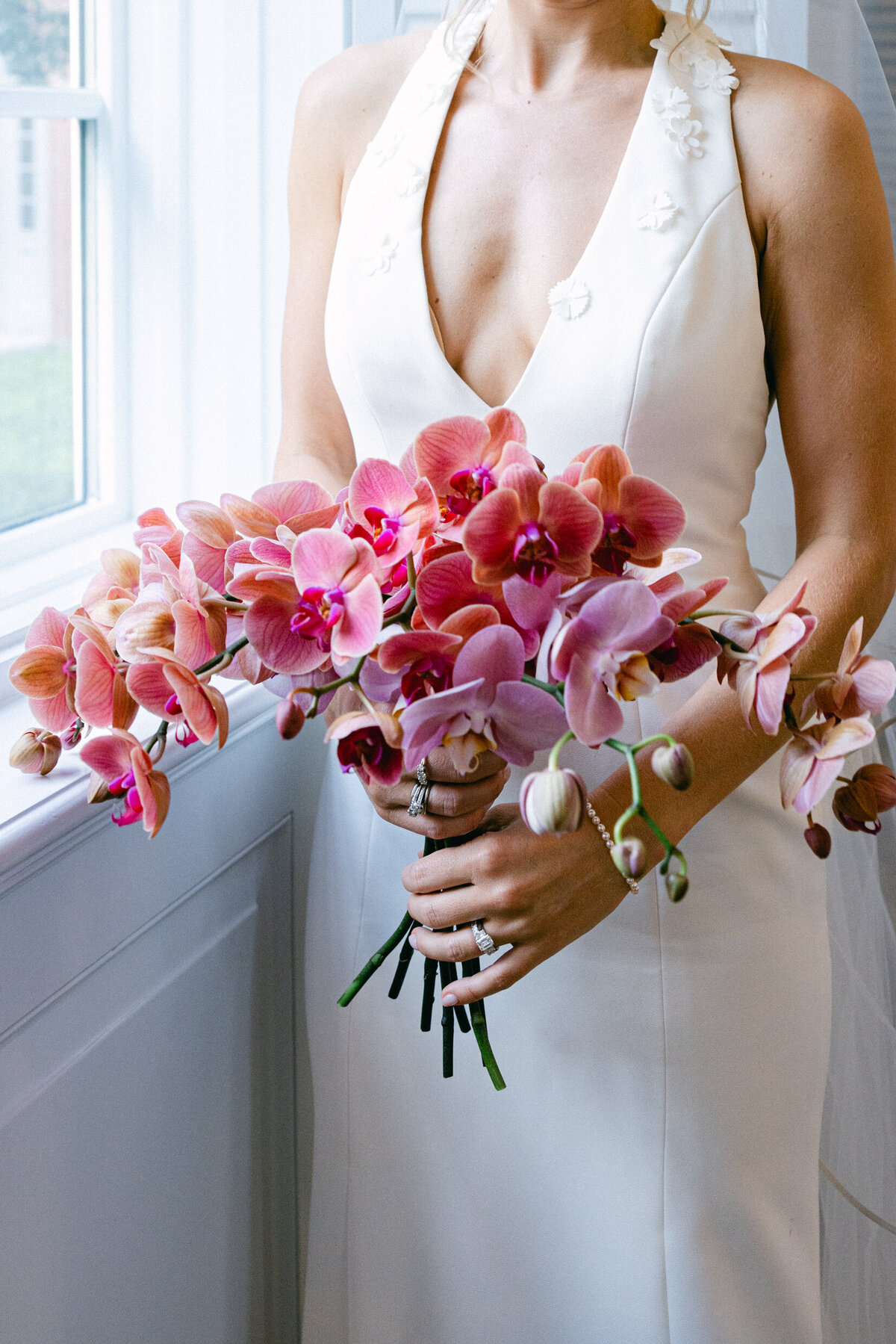 A wedding day photo of the bride holding her bouquet of pink flowers for a picture
