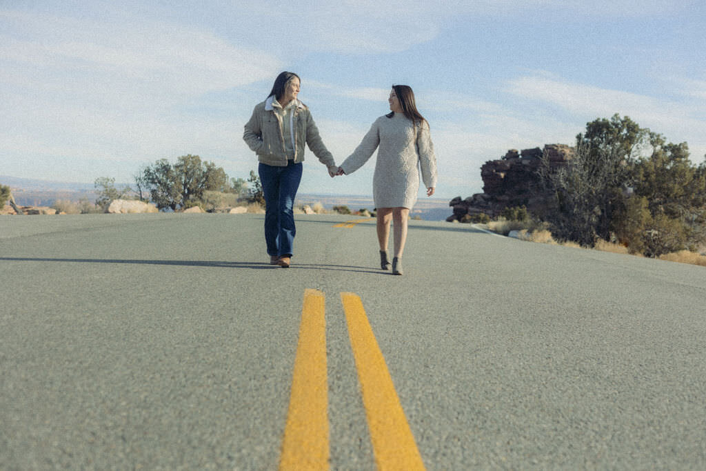 A couple holding hands and walking along a street.