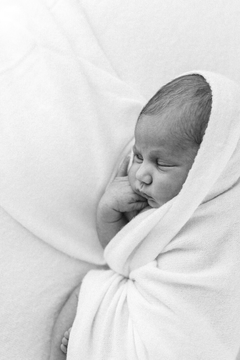 newborn baby tucked up in a white blanket
