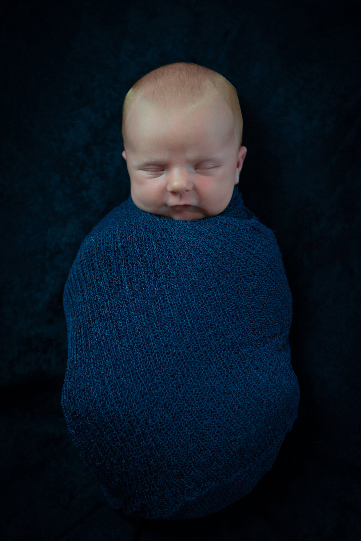 Newborn baby boy in blue swaddle