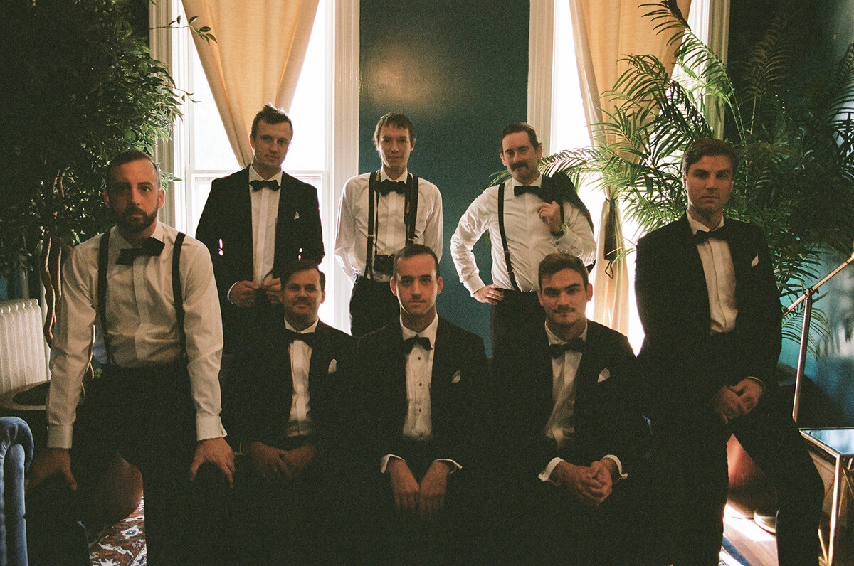 groomsmen sitting on couch while getting ready for the day