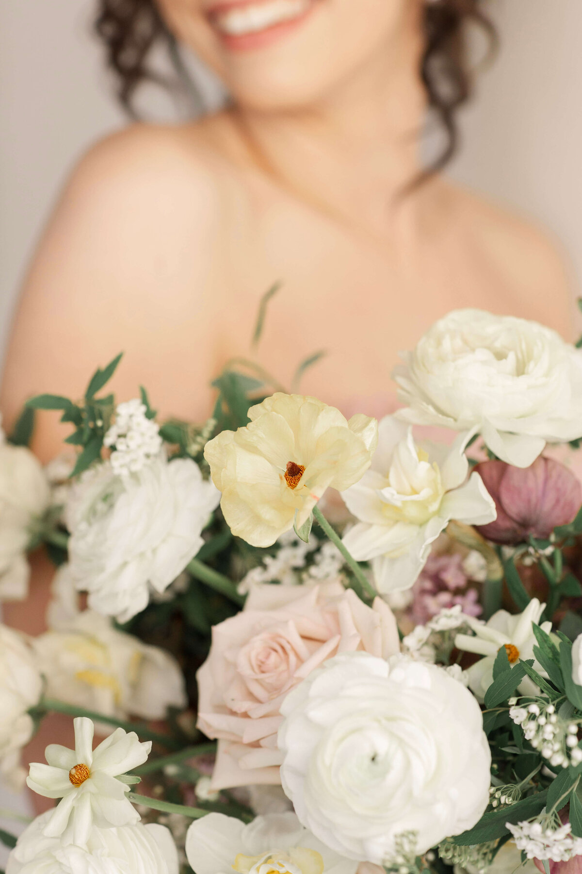 close up of woman holding large bouquet of flowers in ivory, peach, pale pink, lavender and greenery