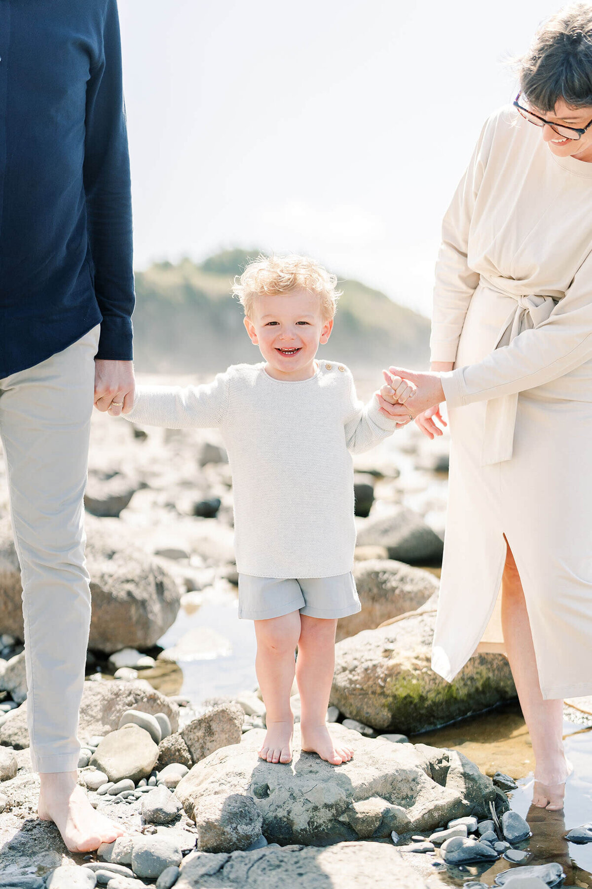 toddler stands on rock during relaxed family session in lincoln city, oregon