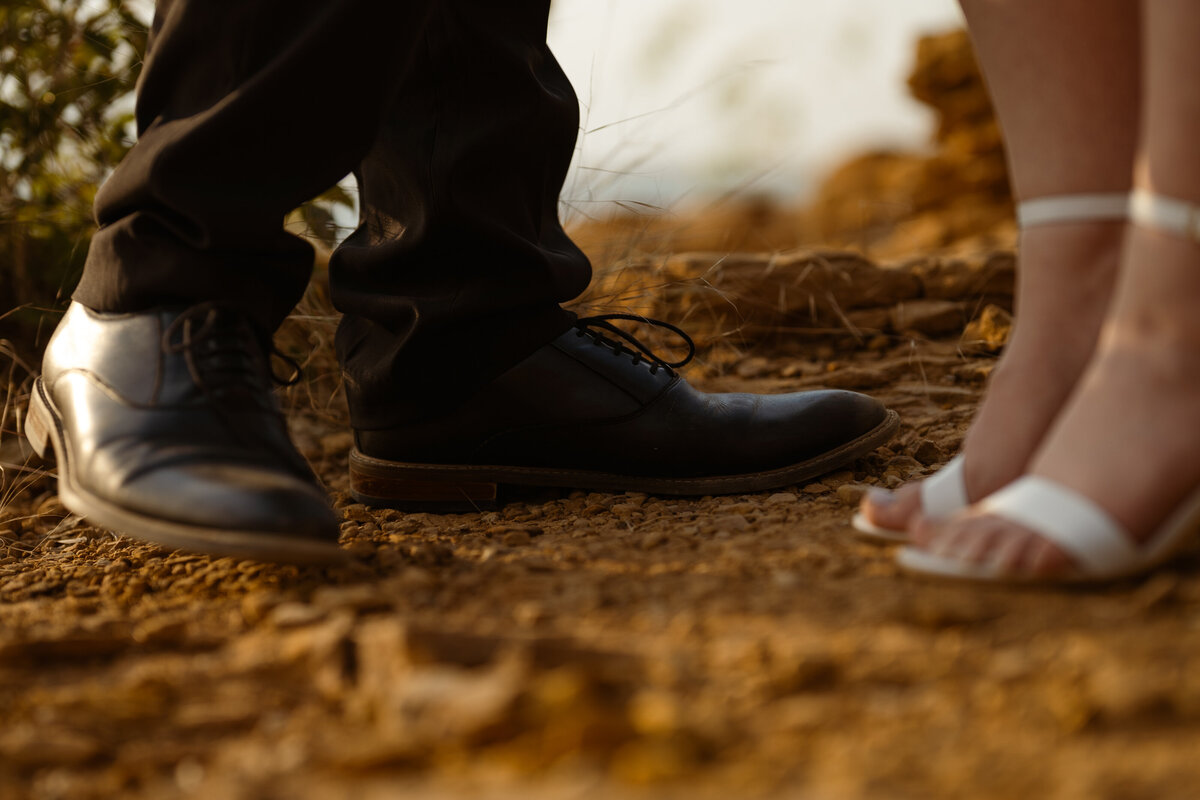 A unique perspective showing the couple’s feet as they stand close by the lake, adding creative detail to their engagement session at Rockledge Park.