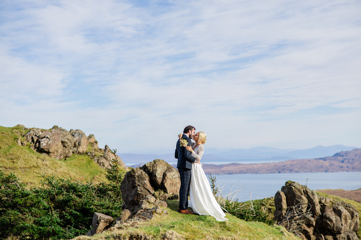 bride and groom kiss and hug on a hilltop