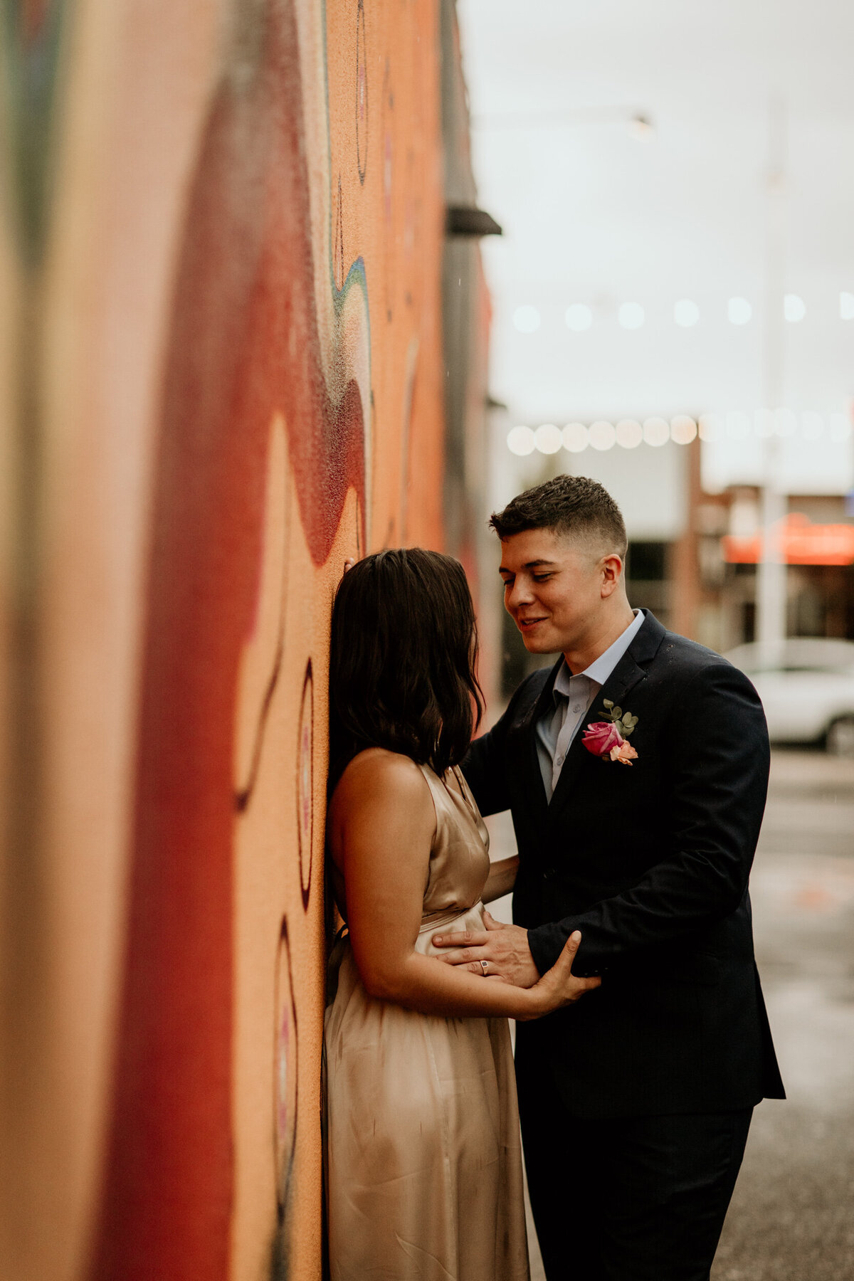 bride and groom leaning against an art wall in downtown Albuquerque