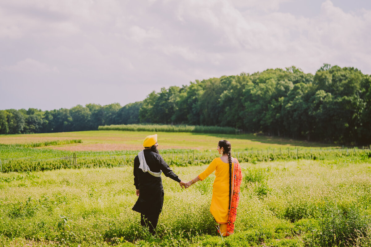 An engaged couple walking together through alstede farms in nj in traditional punjabi clothing