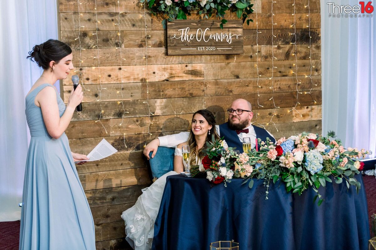 Maid of Honor delivers her toast to the Bride and Groom as they watch from the sweetheart table
