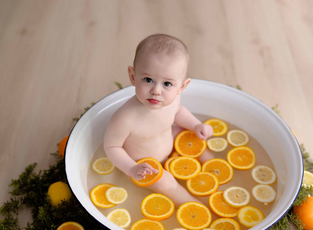 Fruit bath with baby sitting in oranges and lemons. Baby photography by Jenni Nikki at Atlanta photo studio.