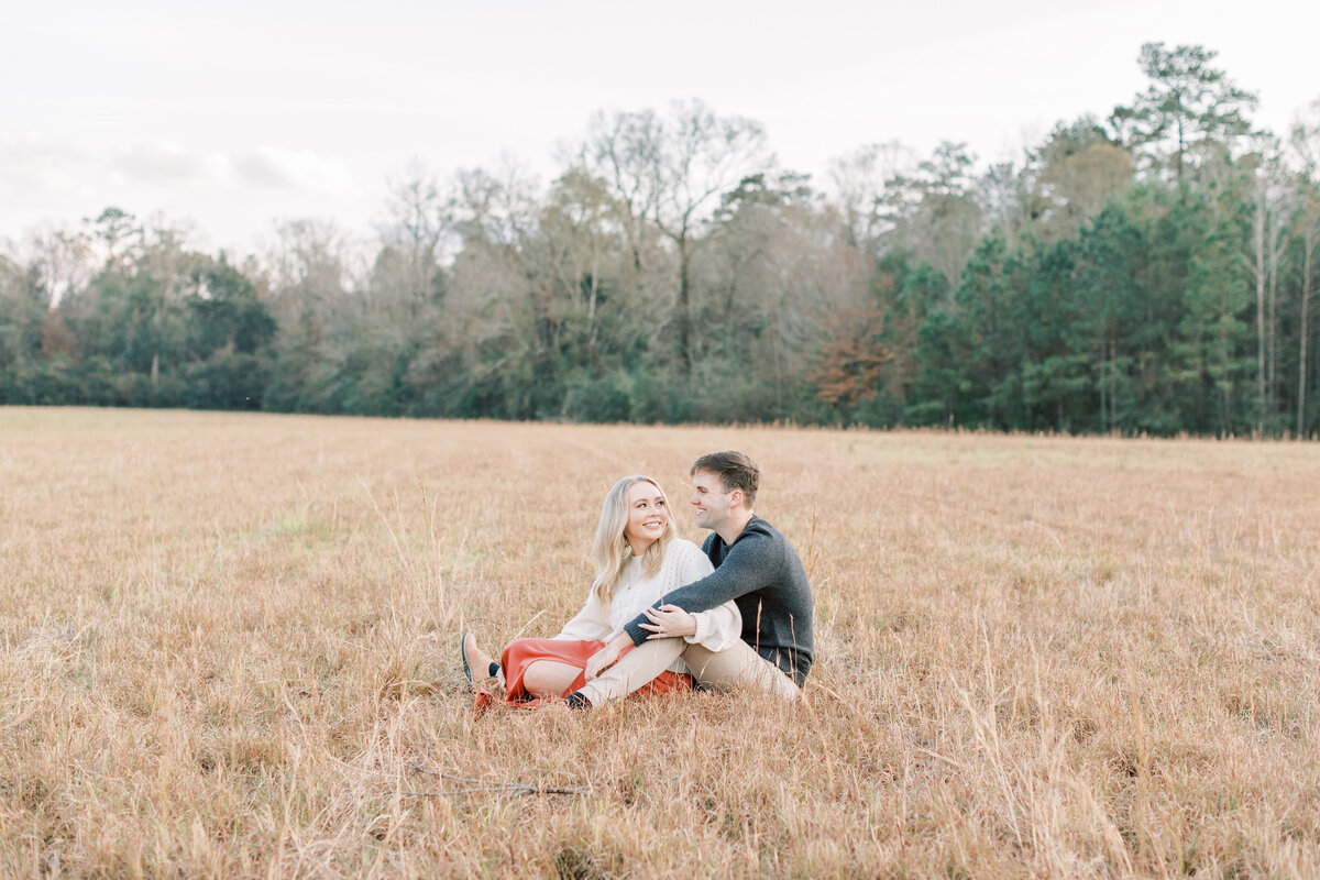 A field surrounds the couple sitting down.