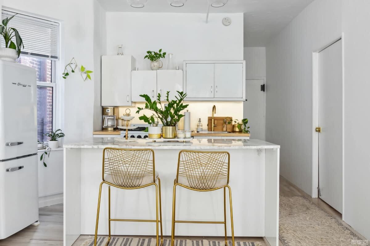 NYC studio kitchen with white marble island, gold barstools, and modern accents for photoshoots.