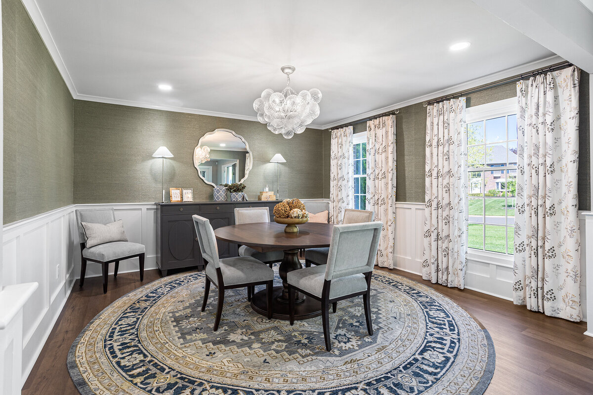 formal dining room with green walls and round table in the middle with chairs